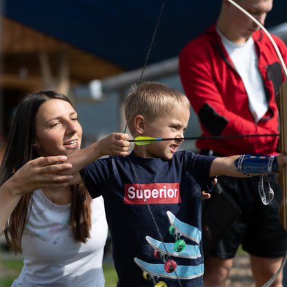 Mutter hilft ihrem Sohn am Übungsareal des 3D-Bogenparcours beim Zielen. | © Hinterramskogler