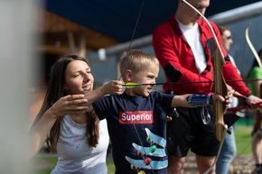 A mother helps her son aim at the target at the practice area of the 3D archery course.  | © Hinterramskogler