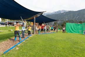 Numerous kids practicing their aiming skills at the canopied practice area of the 3D archery course. 