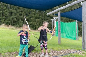 Two kids practicing their skills with bow and arrow at the practice area on Wurbauerkogel.  | © Hinterramskogler