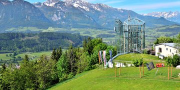 The glass Panorama Tower on Wurbauerkogel in spring with the mountains in the background. 